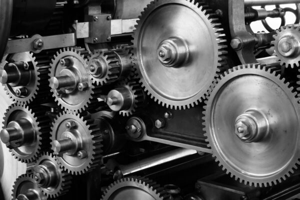 Close-up of intersecting metal gears and cogs in a mechanical assembly, showcasing intricate industrial machinery components.