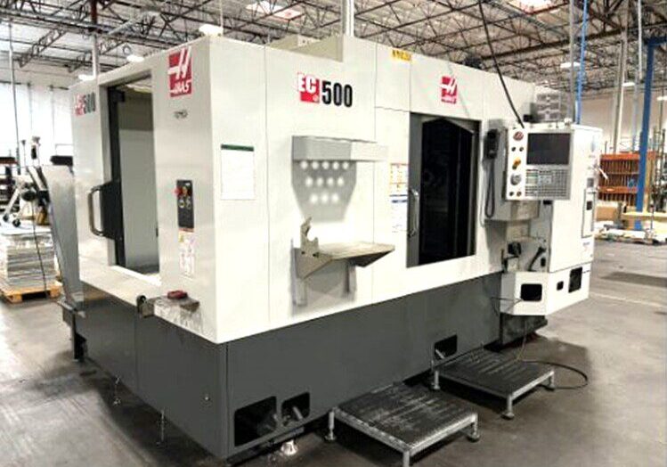 A CNC machining center labeled "EC 500" in a factory setting, featuring control panels and metal platforms.